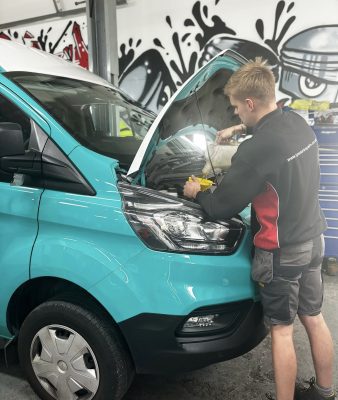 TP Smart Repairs technician refilling engine oil on a turquoise van